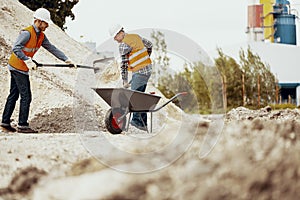 Low angle on workers in reflective vests with shovels and barrow