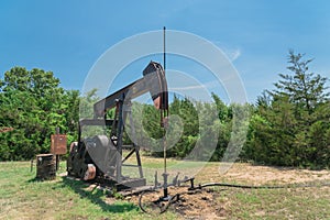 Working pump jack pumping crude oil at oil drilling site in rural USA