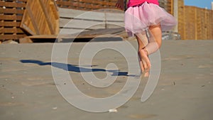 The low-angled shooting of legs of little girl in pink runnung on the beach