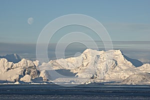 Low Antarctic mountain on which the moon is visible.