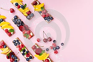 Low calorie snack or dessert from sandwiches with creamy cheese and summer berry fruits on pink trendy background top view.
