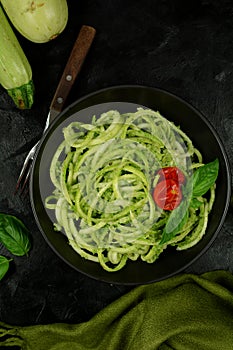 Low Carb Keto Zucchini Noodles with Basil Pesto and Cherry Tomatoes - served on a black background.