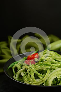 Low Carb Keto Zucchini Noodles with Basil Pesto and Cherry Tomatoes - served on a black background.