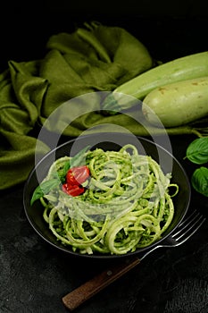 Low Carb Keto Zucchini Noodles with Basil Pesto and Cherry Tomatoes - served on a black background.