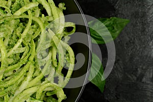 Low Carb Keto Zucchini Noodles with Basil Pesto and Cherry Tomatoes - served on a black background.