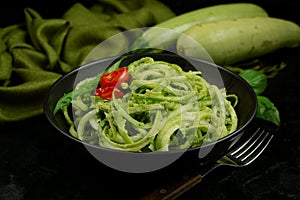 Low Carb Keto Zucchini Noodles with Basil Pesto and Cherry Tomatoes - served on a black background.