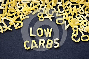 Low carbs phrase spelled with raw letter-shaped pasta on blackboard background photo