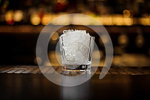 Low cocktail glass filled with ice cubes on the bar counter of restaurant