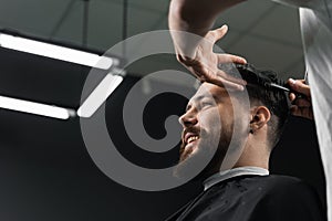 Low fade machine haircut for handsome bearded man in barbershop. Barber with dread locks making hairstyle with a smooth