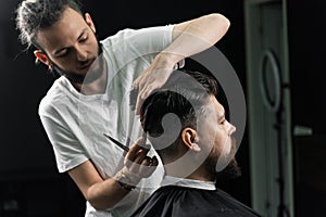 Low fade machine haircut for handsome bearded man in barbershop. Barber with dread locks making hairstyle with a smooth