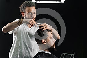 Low fade machine haircut for handsome bearded man in barbershop. Barber with dread locks making hairstyle with a smooth