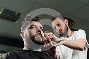 Low fade machine haircut for handsome bearded man in barbershop. Hair cut with a smooth transition.