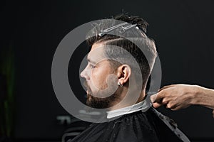 Low fade machine haircut for handsome bearded man in barbershop. Hair cut with a smooth transition.