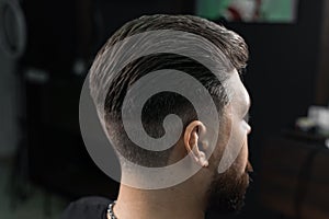 Low fade machine haircut for handsome bearded man in barbershop. Hair cut with a smooth transition. photo