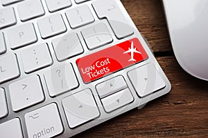 Low fare or cheap flights concept suggested by white computer keyboard with low cost tickets text on red enter key