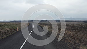 Low flight above road passing through Nordic wasteland. Uninhabited barren plain in countryside. Iceland