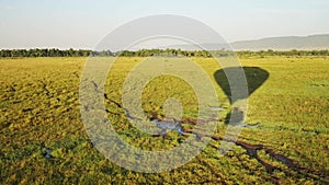 Low flying hot air balloon ride flight over empty African grassland savanna in Maasai Mara National