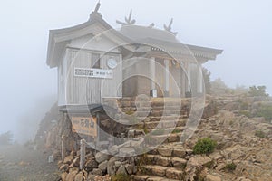 Low fog and mist surrounds small shrine on top of Mt. Ishizuchi in Shikoku, Japan