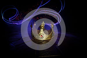 low key image of beautiful kings crown over wooden table. vintage filtered. fantasy medieval period. Selective focus