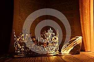 low key image of beautiful queen or king crown in front of old book. vintage filtered. fantasy medieval period