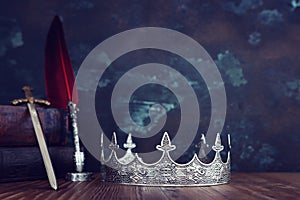 low key image of beautiful queen or king crown next to sword. fantasy medieval period. Selective focus