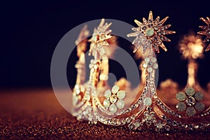 low key image of beautiful queen/king crown over gold glitter table. vintage filtered. fantasy medieval period