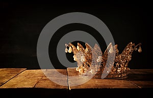 low key image of beautiful queen/king crown over wooden table. vintage filtered. fantasy medieval period.