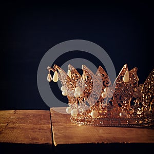 low key image of beautiful queen/king crown over wooden table. vintage filtered. fantasy medieval period.