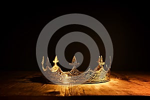 low key image of beautiful queen or king crown over wooden table. vintage filtered. fantasy medieval period