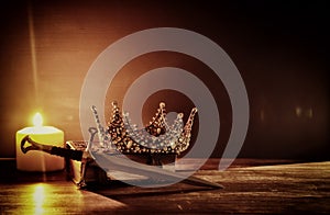 low key image of beautiful queen/king crown and sword. fantasy medieval period. Selective focus.