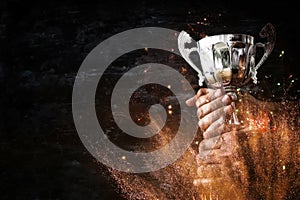 low key image of a man holding a trophy cup over dark background