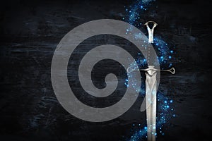 low key image of silver sword with magical lights. fantasy medieval period. photo