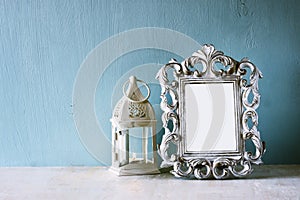 Low key image of vintage antique classical frame and Lantern on wooden table. filtered image