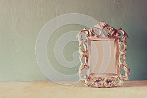 Low key image of vintage antique classical frame on wooden table. filtered image