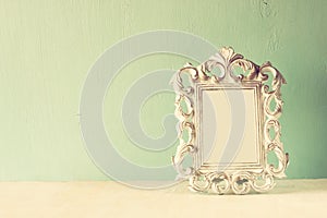 Low key image of vintage antique classical frame on wooden table. filtered image.