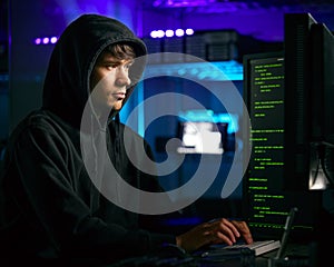 Low Key Lighting Shot Of Male Computer Hacker Sitting In Front Of Screens Breaching Cyber Security