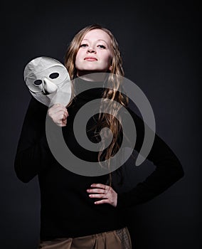 Low key portrait of a beautiful woman holding mask