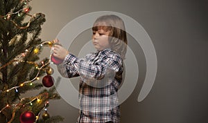 Low key Portrait of happy boy decorating Christmas tree