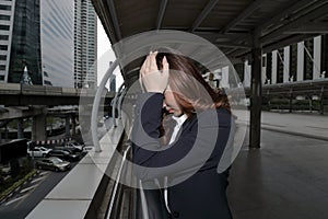 Low key portrait of stressed frustrated young Asian business woman touching head with hands and feeling tired or disappointment at