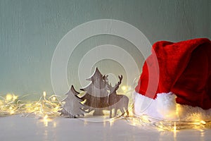 Low key of wooden christmas tree and deer next to santa hat