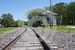 A low level view of a single track railway line on a sunny day, with the Chicago and Alton Railroad Depot building on the right ha