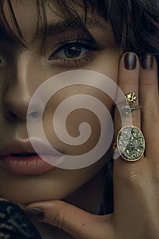 Low light portrait of a beautiful girl with amazing green eyes, professional nude make-up and fashion golden accessories