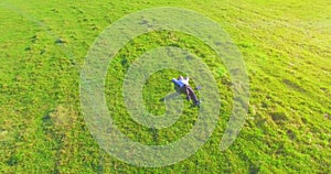 Low orbital flight around man on green grass with notebook pad at yellow rural field.