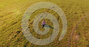 Low orbital flight around man on green grass with notebook pad at yellow rural field.