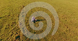 Low orbital flight around man on green grass with notebook pad at yellow rural field.