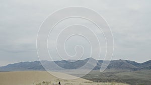 Low panorama of mountains and cloudy sky. Action. Lonely man on hill on background of horizon with mountains. Lonely