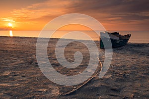 Low perspective with a rope leading to a fishing boat on the beach at sunrise