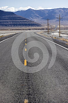 Low point of view lonely empty highway stretching for miles into the desert into the mountains