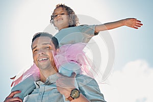 Low Portrait view of a father carrying his daughter on his shoulders outdoors.. Low Portrait view of a father carrying