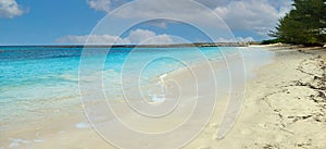 Low prfile beach photo of sand and water with blue sky.